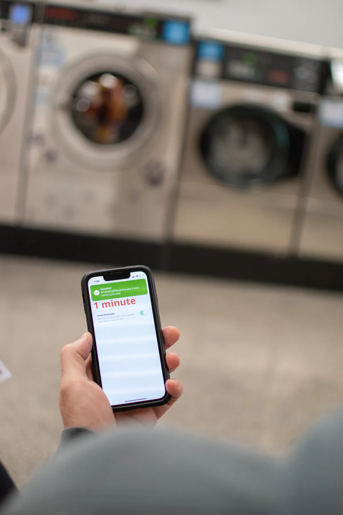 Customer watching the SpeedQueen app countdown while machines run at Coast Laundromat Whangaparaoa