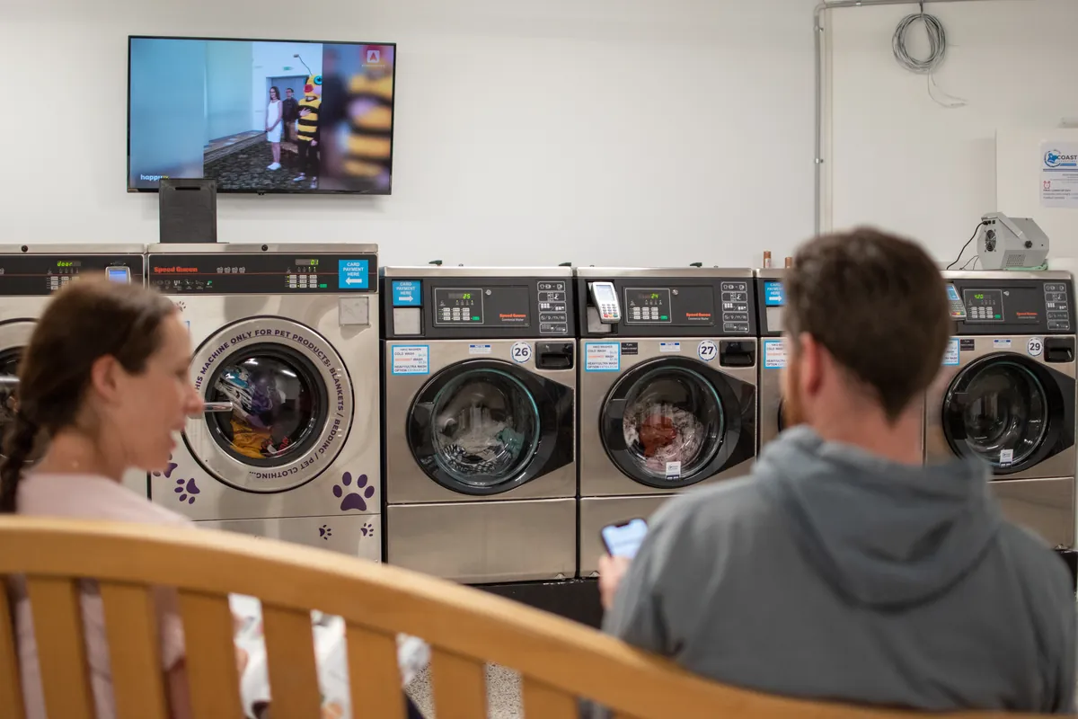 Customers waiting comfortably in front of the washers at Coast Laundromat, Whangaparaoa Peninsula